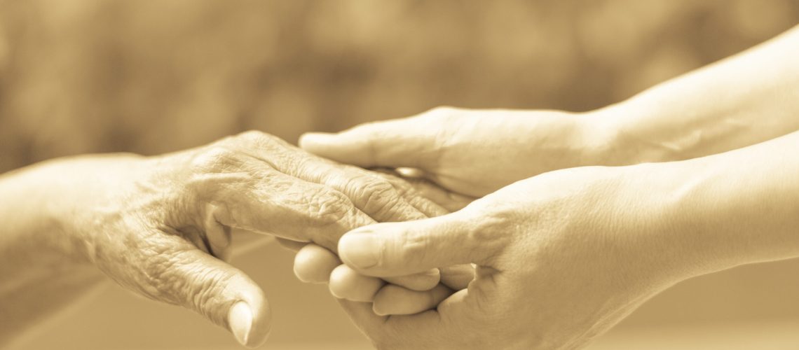 Caregiver, carer hand holding elder hand in hospice care. Philanthropy kindness to disabled old people concept.Happy mother's day.
